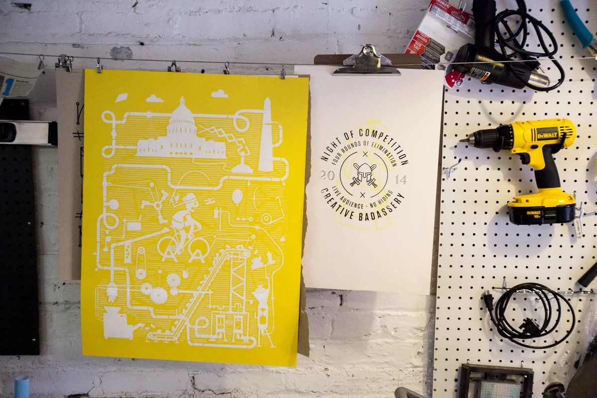 A yellow Artcrank DC poster drying alongside its proof print.