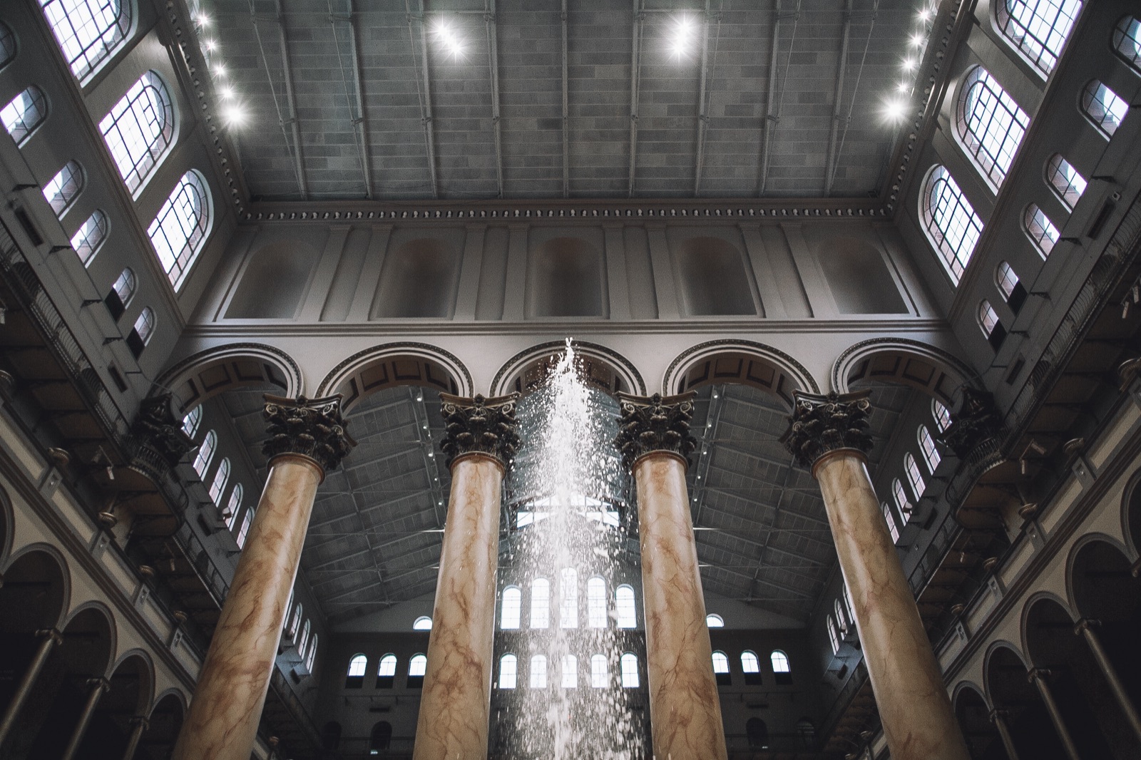 National Building Museum interior shot from below, marble columns flanking the central fountain shaft.